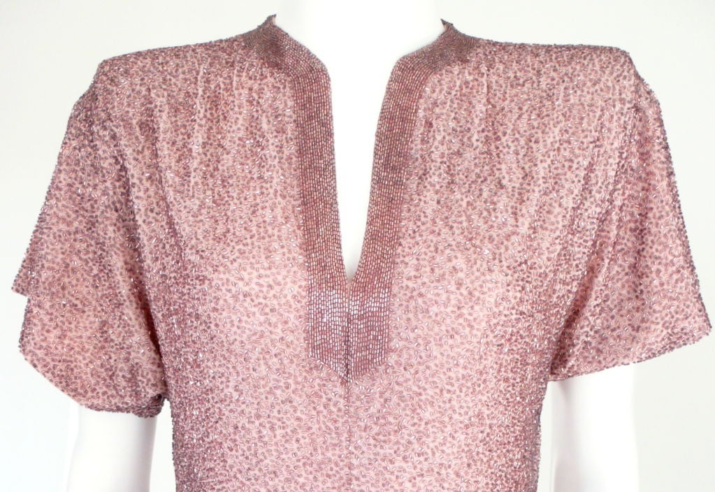 Stunning short sleeve gown, encrusted in small pink glass bugle beads throughout. Backed on light pink silk crepe, padded shoulders and a gathered drop waist. Kept in pristine condition.