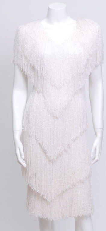 This hand loomed, knit fringe dress features a v style five tier layering, and enhanced shoulders.