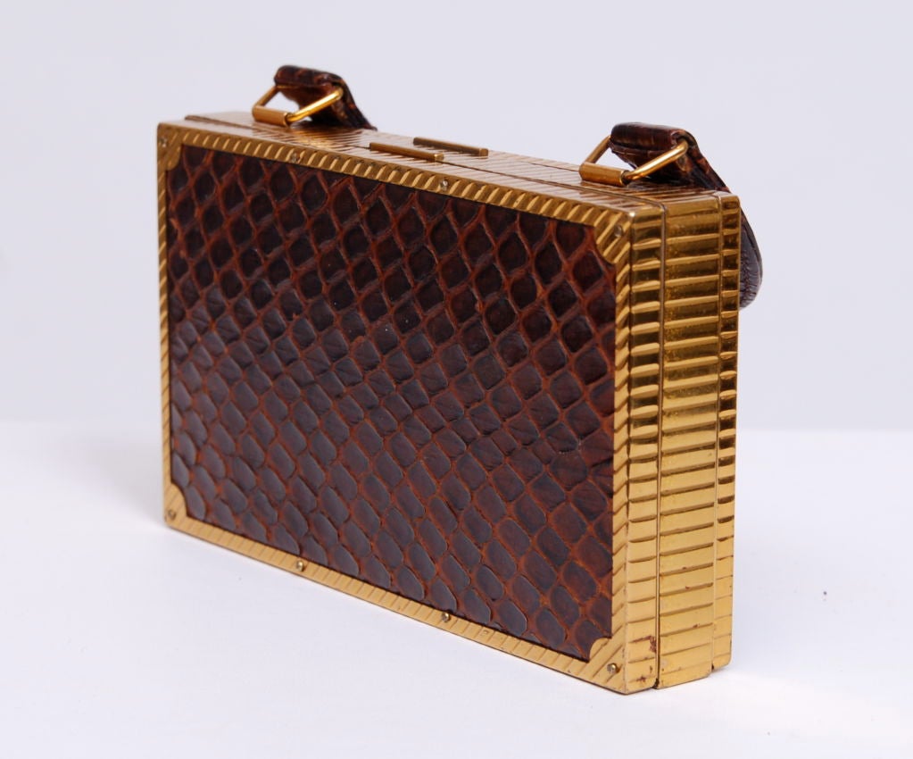 Compact dual compartment metal purse with chocolate brown snakeskin covered front, back and handles. Interior mirror, comb holder (comb missing), cigarette compartment.