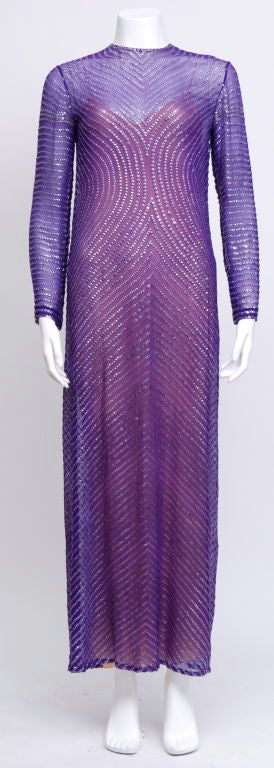 This long sleeve Halston, crew- neck, sequin gown features a hook eye closure and silk slip. This dress is embellished with layers of purple iridescent sequins. This long gown is perfectly chic and retro.