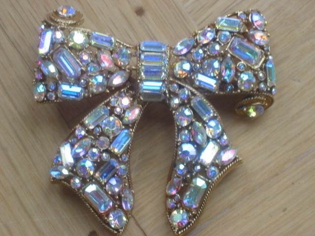 Gorgeous Vintage 1980's Jeweled Bow Pin from Richard Serbin<br />
<br />
This stunning pin is made of casted brass metal plated in a gold tone. The lovely bow is encrusted with mixed shapes of genuine Swarovski Austrian Crystals. The crystals are