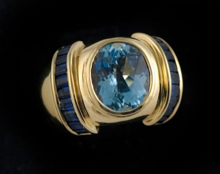 An 18 karat gold, sapphire and aquamarine ring - one-of-two-made - by Albert Lipten, of New York, with a central oval aqua marine center stone (3.20 karats) and with sapphire (1.60 karats) baguettes on each side of aquamarine stone.  Weight 19.07