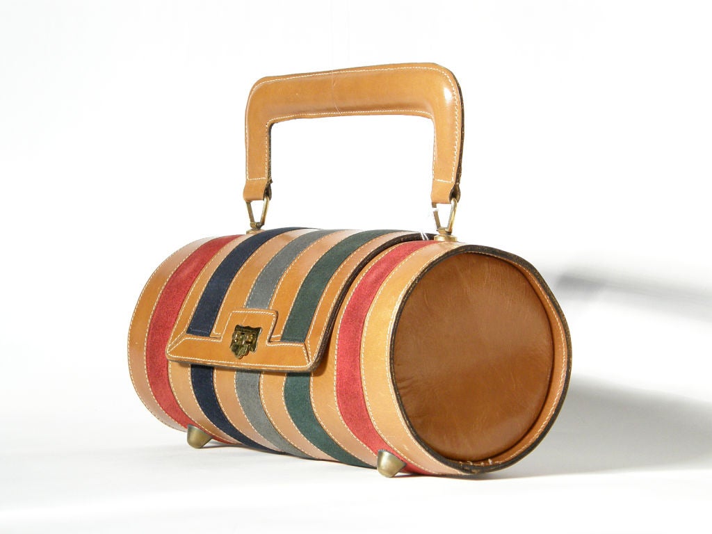This striking, barrel-shaped handbag was made in Italy for Josef, c. 1955. It has alternating stripes of tan leather and multi-colored suede. The roomy interior is unlined.

Bag measures 10" high to top of handle.