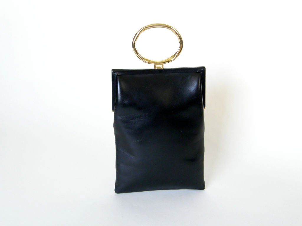 This unusual Roberta di Camerino handbag has a brutalist treatment to the hardware. The ring shaped handle and the buckles on the front have an intentional irregularity that gives them a kind of primitive charm. The body of the bag is black leather.