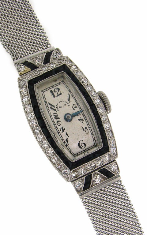Elegant and classy diamond, black onyx and platinum ladies watch created by Patek Philippe in the 1930's.<br />
It has a beautiful tourneau shape face encrusted with single cut diamonds and inlaid with black onyx. White dial has black hand-painted