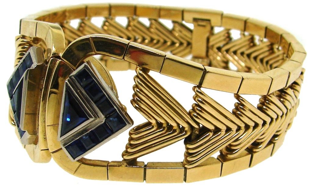 Fabulous Retro watch/bracelet created by Gubelin in Switzerland in the 1950's. It is made of yellow gold and has two triangle-shape white gold accents set with French cut sapphires. The accents serve as a cover of a watch that is hidden behind them.