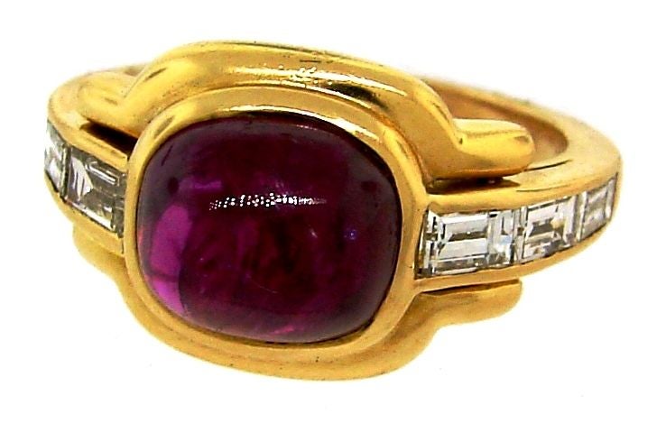 This elegant and classic ring was created by Bulgari in the early 1970's. It is made of 18k yellow gold. In the center it is set with a wonderful color Burmese cabochon ruby with three graduating tapered baguette diamond accents on each side of the