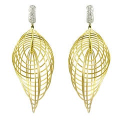 A pair of mobius style gold hoops earrings with diamond tops.