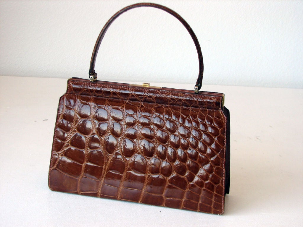 Fine vintage crocodile 'Kelly' hand bag. Authentic & rich 'tobacco' brown skins item fully brown leather lined with gilt metal hardware & glides. Pristine interior features 2 open & single zipper pockets. Matching skins handle features 5 1/4