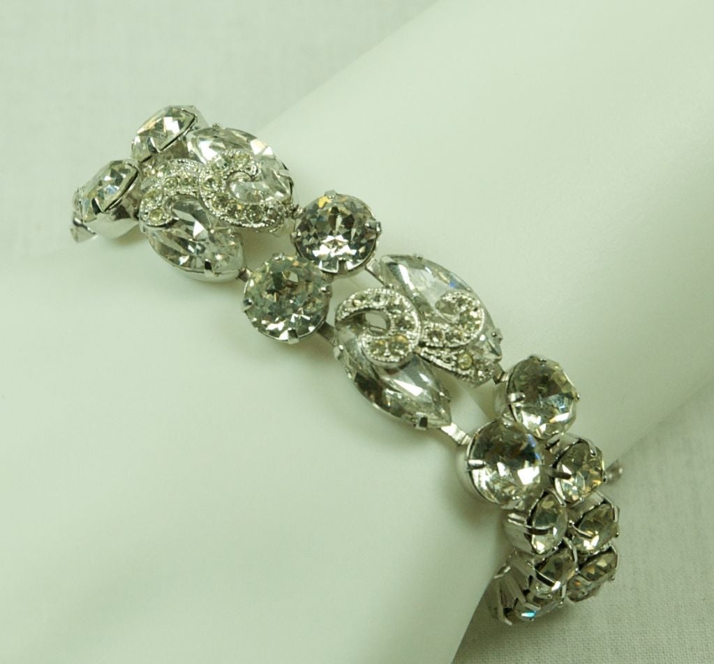 Featured is an Eisenberg rhinestone bracelet. It has big round stones and center has marquis shape with layered shapes of smaller stones. It has a safety chain is signed.