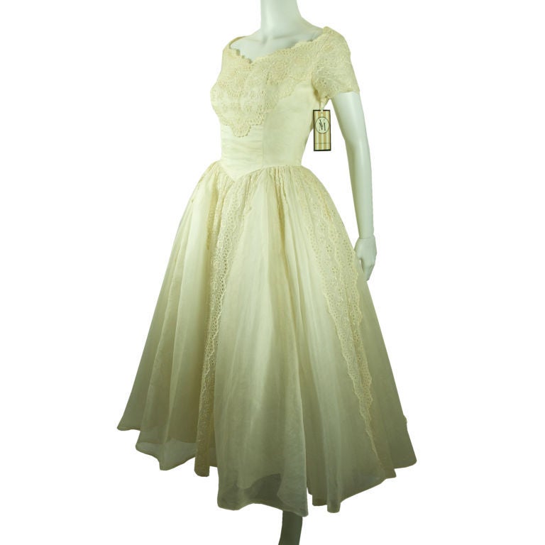 Featured is a beautiful wedding dress from the 1950's.  The bodice is beautiful gracing the neckline and finishing with lace short sleeves. It has  a full skirt of organza and lace eyelet with a layer of tulle and satin. The dress is shown with a