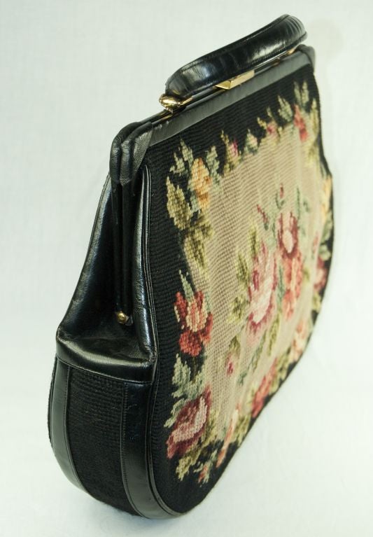 Fantastic extra large tapestry handbag. This size is very hard to find and are sought after!  The tapestry is is of dusty rose color roses,green leaves. with black and beige background. The handle is leather. The interior has a metal zipper pocket