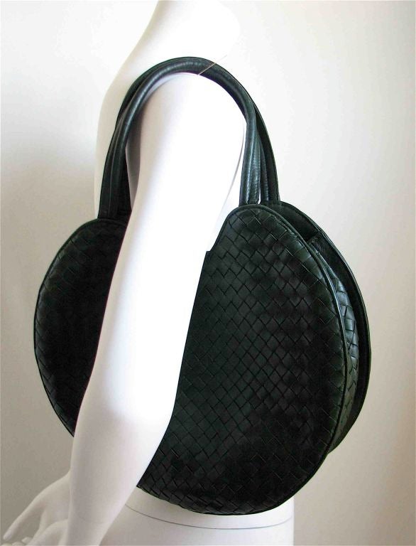Forest green circular woven leather bag. Can be worn over shoulder or held by hand. Fully lined in back. One interior zippered compartment. Approximate measurements are 12
