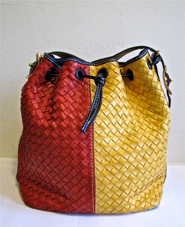 Very vivid woven leather bag from Bottega Veneta. Shiny gold hardware. Colors are true red, bright yellow, and royal blue. Fully lined in nude leather. Interior zippered compartment. Bag measures approximately 11