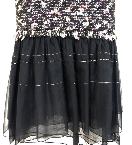Tapered black fantasy tweed boucle dress with spaghetti straps, drop waist and flounced ruffle hem. Fantasy tweed is black wool blend boucle interwoven with silver, peach, pink, yellow, white and blue.  Hem is black tulle with bands of silver and