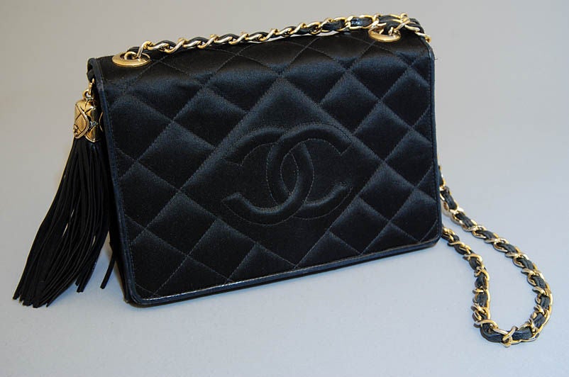 This adorable satin bag hails from CHANEL. Perfect for day or eveving, this bag would make an amazing addition to any accessories collection! Composed of black, quilted satin with stitched, CC logo in front. Iconic leather and gold chain strap. Cute