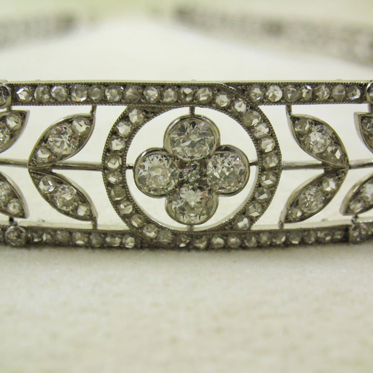 The slightly tapering openwork band of floral and foliate motifs, set throughout with old brilliant, single and rose-cut diamonds, diamonds approximately 14.00 carats total, mounted in platinum, circa 1910, signed 