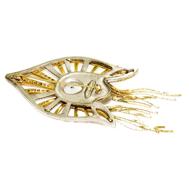This is a Signed and numbered Brooch by Erte set with Sapphires and Diamonds and having a Carved Mother of Pearl face.