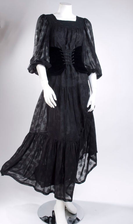 1980's Yves Saint Laurent Gypsy Gown.<br />
Black  flowers on black viscose chiffon, three-tiered and a black velvet corset belt. Slip on, two buttons on the back, elastic at sleeves. Lining has a strait cut 36