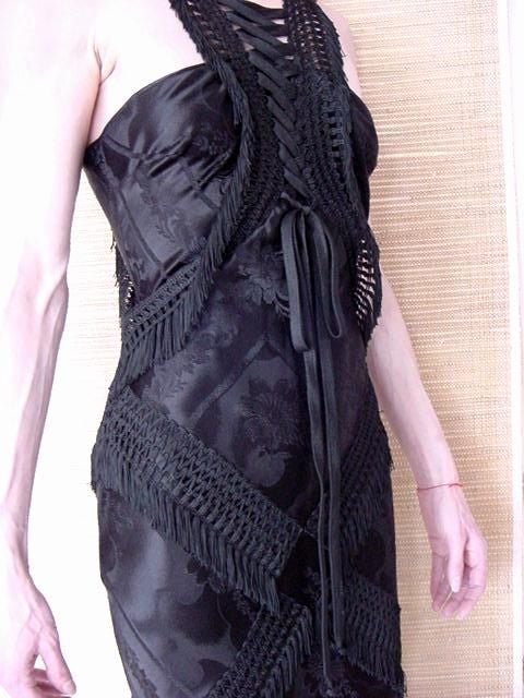 Nothing less than a piece of art.
Jet black with a black on black brocade print on the fabric. 
Incredible fitted cut with a swirl from below the knees to the hem.
Beautifully detailed embroidery work with fringe 'wrap' at figure flattering