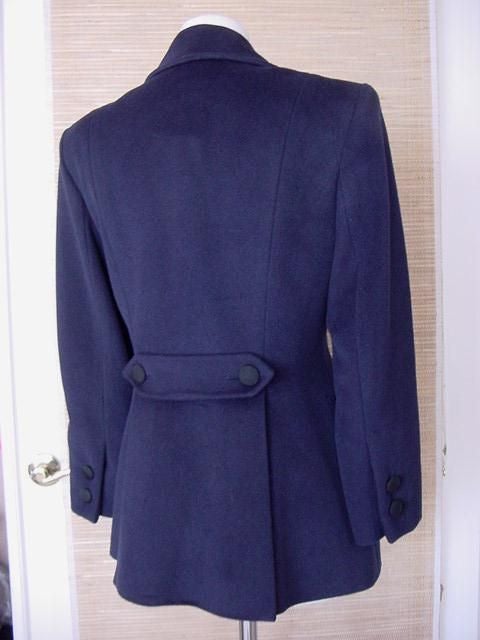 Ines de la Fressange rich navy lush warm cashmere blend.
4 on 2 Double breasted jacket with 2 sculpted flap pockets.  
The actual pockets are on interior, the flaps are sculpted with a button.
The rear has a double centered vent created by a 'flap'