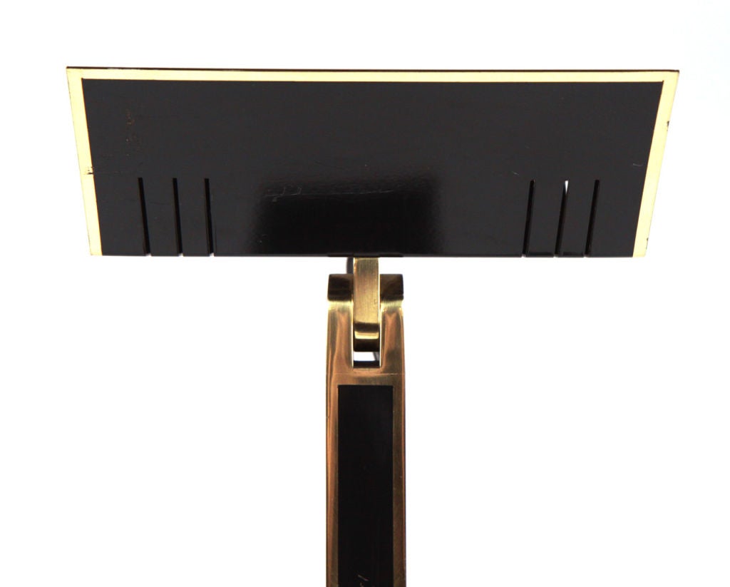 A chic very tall torchière finished in black lacquered metal with polished brass details outlining the inverted triangular shade, the long square pole and the rectangular base, with dimmer. Stamped [Relco]. Manner of Pierre Cardin. Italy, circa 1970.