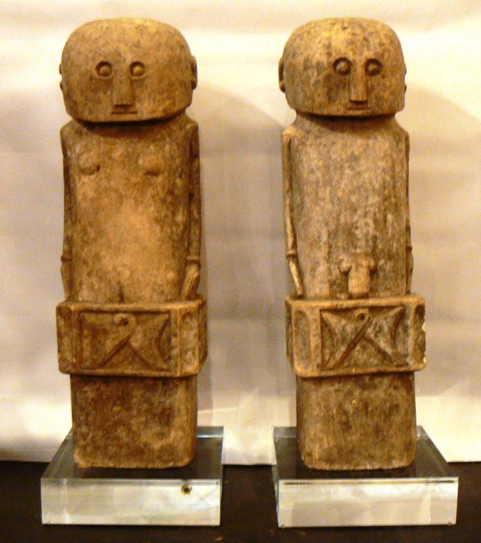 Carved stone male and female figures from the Flores Islands. Each figure is mounted on concrete black pedestals.