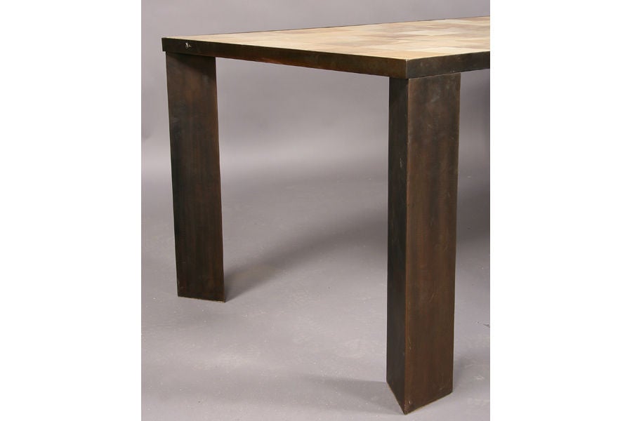 Stunning and unique dining table with a parchment top in a patchwork configuration. Triangular table legs made of a washed bronze steel.