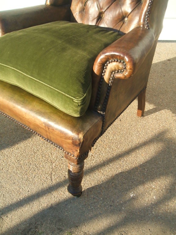 A late 19th C English wing chair in leather, with great patina and original casters. Original seat cushion in green velvet.<br />
Seat Height:20