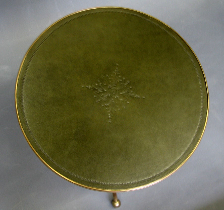 A Campaign style, folding tripodal side table model, dubbed the "Emergency Cocktail Table," executed in brass with blind tooled leather top surrounded by a brass gallery. Alternate leathers available. Please allow 2 weeks for leather