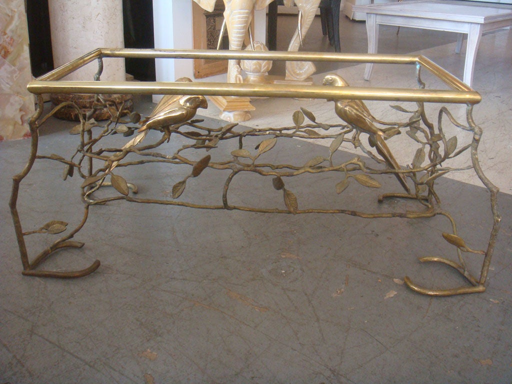 A great coffee table in brass having birds resting in a twig and leaf form base. Thispiece has excellent craftmanship and detailed beautifully. It appears that the twigs and leaves have patinated over time and the birds polished. There is a glass
