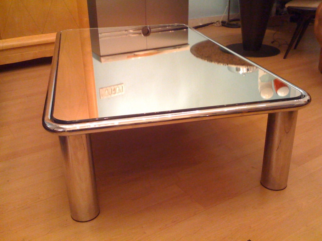 A large rare sleek cocktail table by Italian designer,Mario Bellini for Cassina furniture. The table is a heavy chrome with a mirrored glass top.Original label . Sale price noted. reg $ 7800