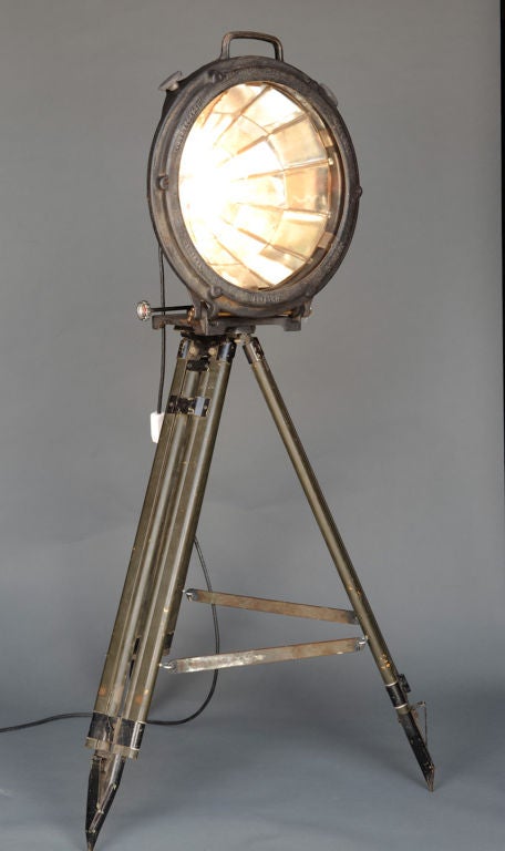 A handsome mirrored spotlight from the 1920's mounted on a WWII tripod.  The lens is a early convexed piece of glass.  That this head survived intact is a thing on wonder.  The light has been freshly rewired. It has a wonderful glow because of the