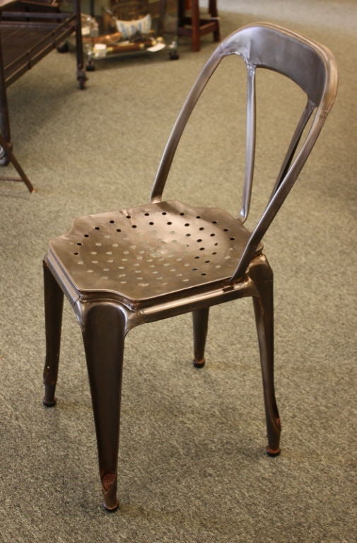 A pair of perforated-seat steel bistro chairs from 1940's France.  Wide curved seats and slightly reclined backs make these chairs very comfortable.  Tapered legs.  Second height measurement is for the seat. Legs have been fitted with inserts to