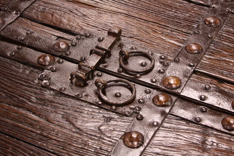 A large antique Chinese door as a coffee table. Terrific look,with iron lock and banding, with some old leather decoration.  New base to compliment the top.  Dramatic look for a large space. Top is in two parts, and lifts off base.  Reduced. NT