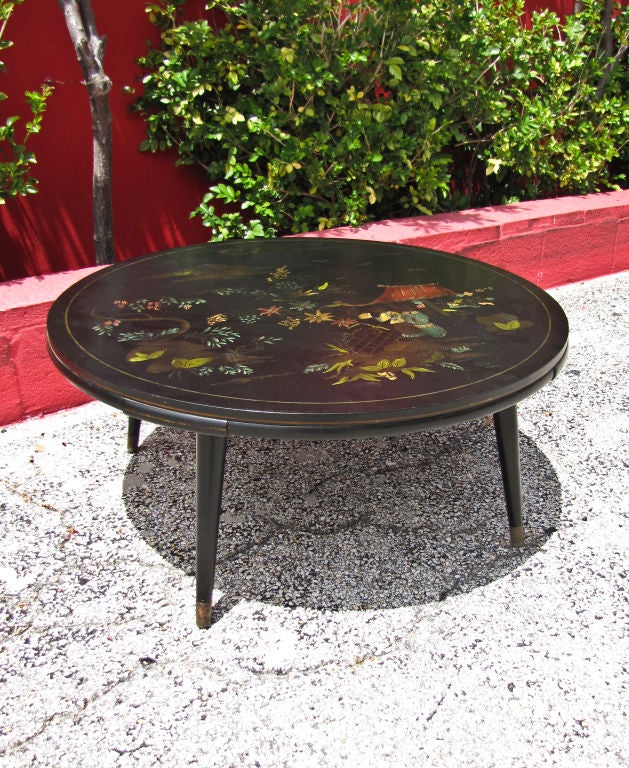 A chic 1950s modern round black lacquer coffee table with Chinoiserie painting on the top. The 50's style legs are finished with brass at the end. There is a 1/4