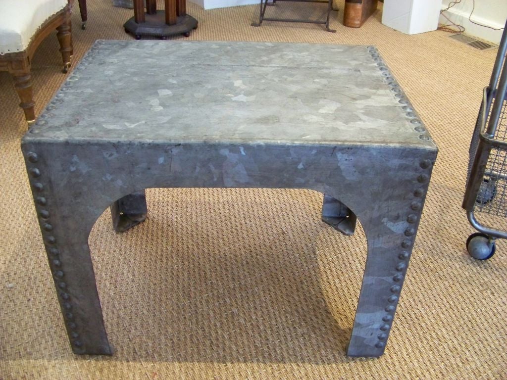 An end or coffee table made from a heavily riveted steel industrial piece.