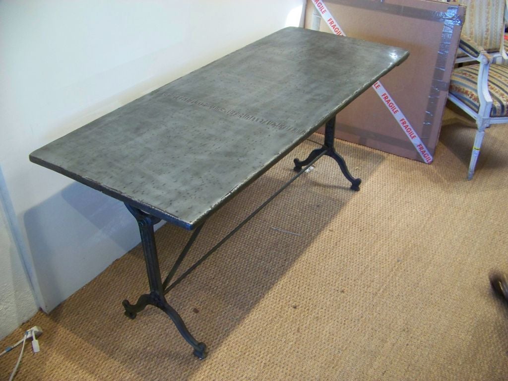 A bistro table with a castiron base and a zinc covered wooden top.