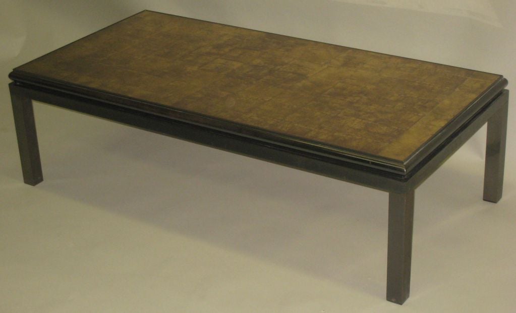 French Mid-Century Modern coffee table by Guy Lefebvre for Maison Jansen with base in dark grey enameled steel and the top of elegant gold leaf reverse painted glass (verre églomisé) which is cantilevered slightly over the supporting