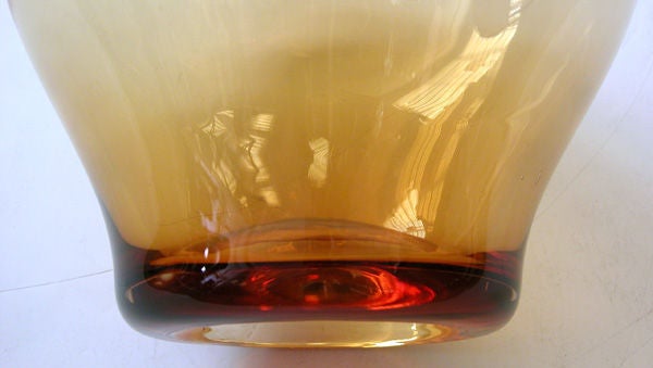 A shapely American amber colored glass apple by Blenko; the arching stem above a robust body tapering at the base