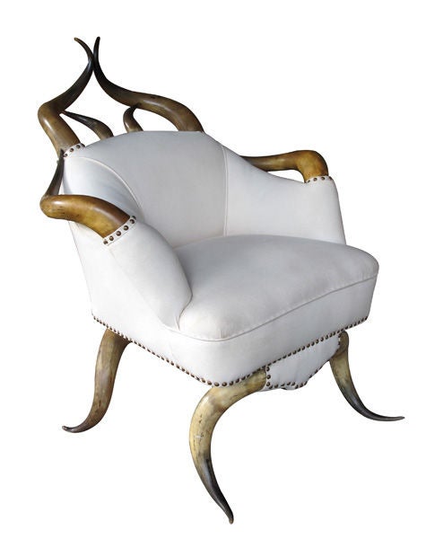 A large-scaled American steer horn upholstered club chair; the openwork crest comprised of curvaceous steer horns; above an upholstered tub chair all raised on downturned steer horn legs