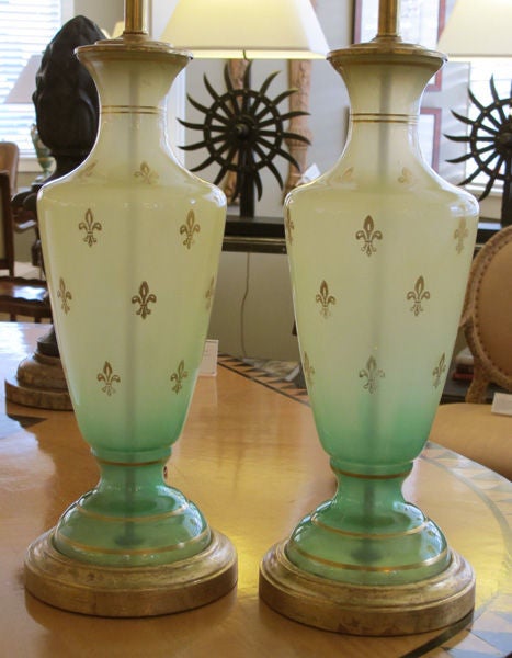 A pair of American mid-century frosted apple-green urn-form glass lamps with gilt fleur-de-lys decoration; by Frederick Cooper, Chicago; each urn-form lamp in a graduated apple-green frosted glass; adorned overall with gilt fleur-de-lys decoration