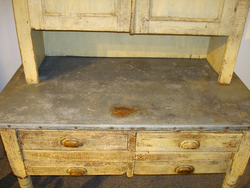 FOLKY 19THC ORIGINAL CREAM PAINTED TWO PIECE BAKERS CUPBOARD FROM PENNSYLVNIA WITH FLOUR BIN DRAWERS IN BASE. ALL ORIGINAL HARDWARE AND PAINTED SURFACE. THE CUPBOARD IS TWO PIECES AND CAN BE SEPARATED. THE ZINK TOP IS ORIGINAL TO THE PIECE AND WAS