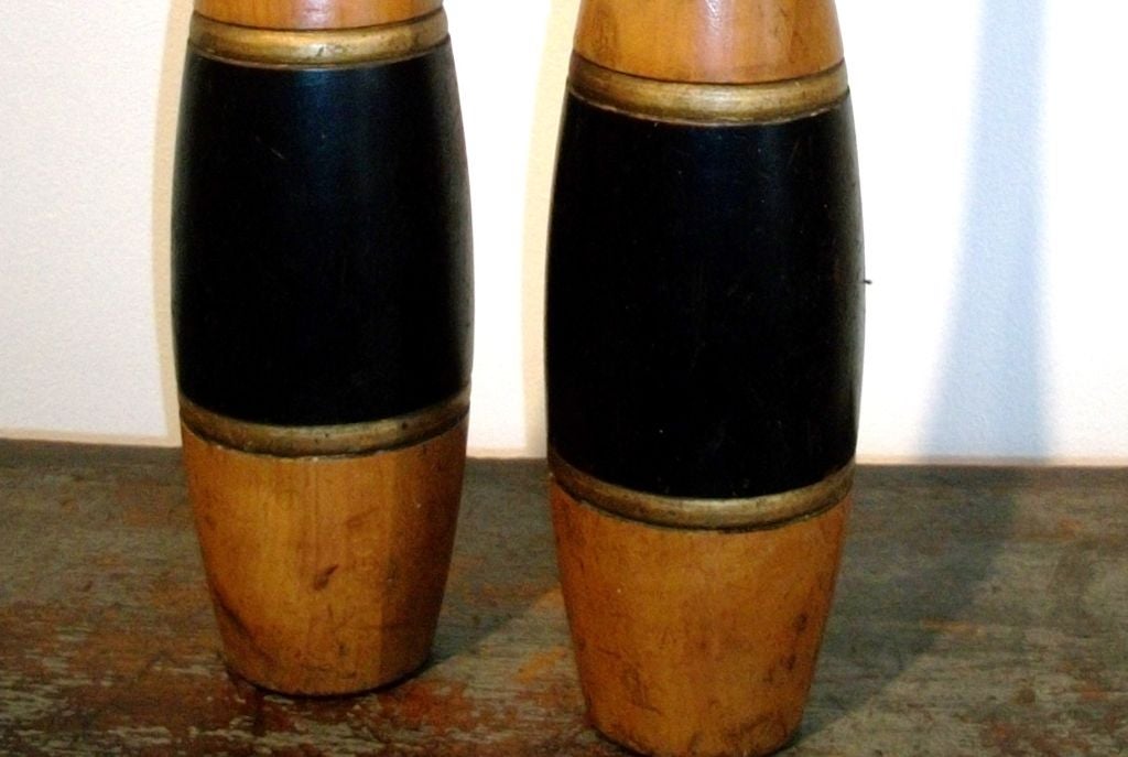 Pair of 19th century painted and natural juggling pins. The pair of pins have a gilded/painted stripe above and below the wide black painted band. The condition is good and the wood is pine.