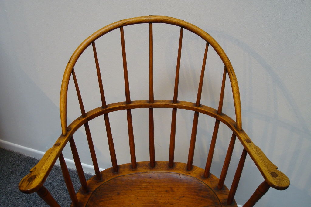 18THC NEW ENGLAND BOW BACK WINDSOR ARM CHAIR W/SADDLE SEAT. MADE OF POPULAR AND HICKORY WOODS. THE CONDITION IS GOOD AND HAS A WONDERFUL MELLOW PATINA. THE ARMS HAVE A WONDERFUL CUT OUT AND THE SPINDLES PROTRUDE THROUGH THE ARMS.