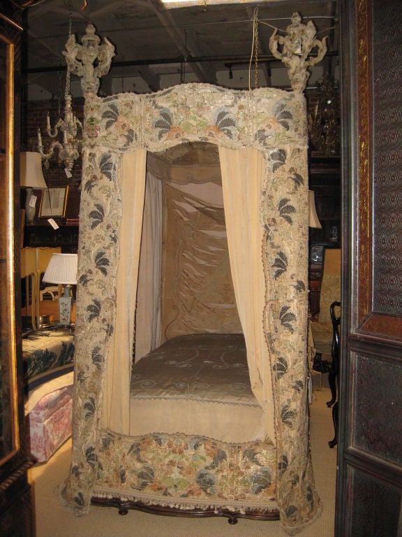 Dreamy bed from a castle with carved walnut foot rail covered in 17th C textile and other later 19th C textile over mattress and draped on back---this is tattered and needs to be replaced but the earlier textile is stable and beautiful