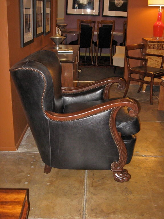 Amply scaled Swedish neo-gothic winged back chair in Oak. Crested arm and lions feet. Restored and reupholstered in black leather. Copper colored nail heads. Loose cushion seat.