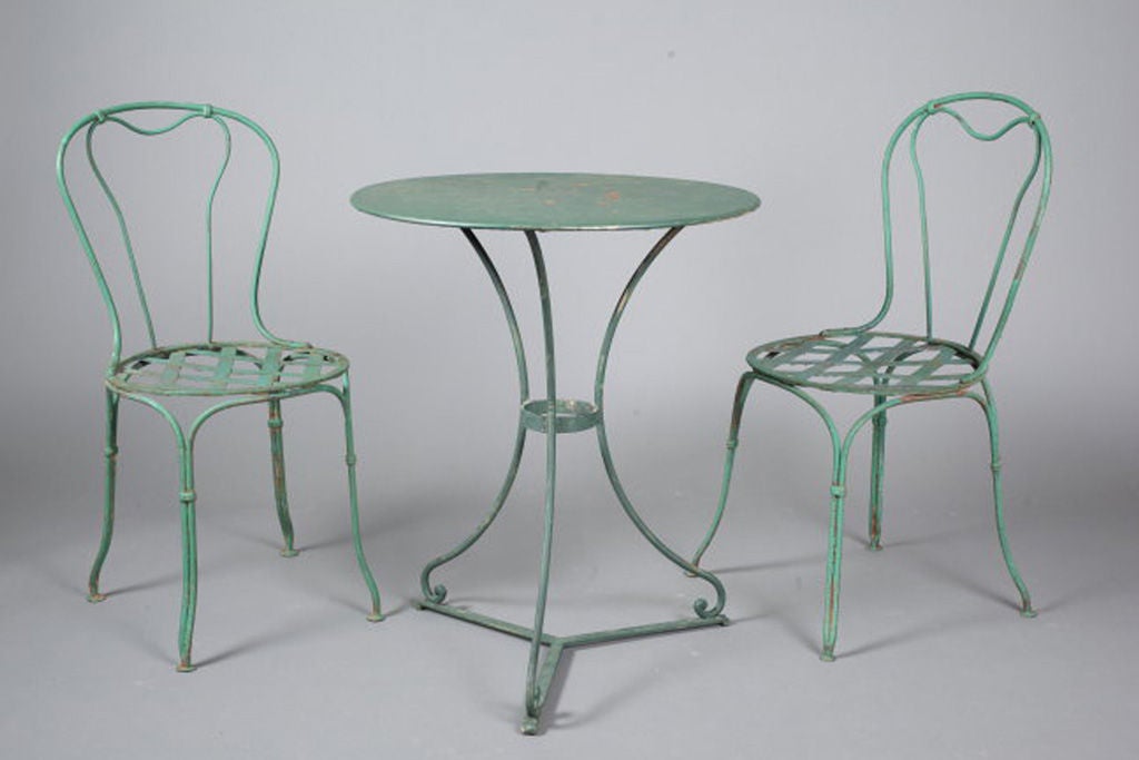 Pretty French 1920's wrought iron table and chairs of typical form, the table with flat iron top over scrolled legs, the chairs with lattice seats, all in lovely old paint.