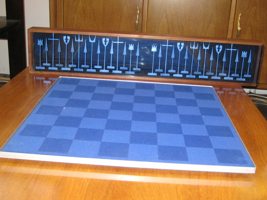This complete chess set with board and display box were produced in limited quantities by Alcoa Aluminum in 1962 as presentation sets and designed by industrial designer Austin Cox.  The walnut display box has a blue-tinted plexi cover and is