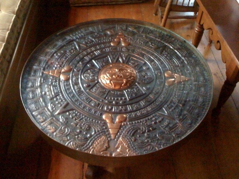 Mayan calendar, repousse hand hammered copper top coffee table. Hand carved wood base with mortised joints. The top is banded by a thick copper rim-the table is heavy and very well crafted-striking apperance. The top is protected by inset glass.